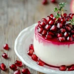 A Panna Cotta Topped With Pomegranate Glaze And Fresh Pomegranate Seeds